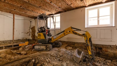 Bagger bei Renovierung in einem Raum mit Backsteindecke.