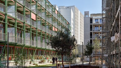 Moderne Gebäude mit grünen Metallstrukturen und Bäumen im Hof.