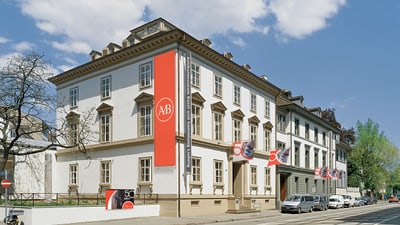 Historisches Gebäude mit roten Bannern und moderner Kunstinstallation.