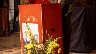 Tanja Grandits steht am Rednerpult mit Blumenstrauss