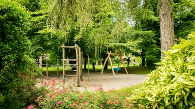 Spielplatz in einem Park mit Schaukeln und Blumen.