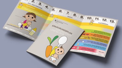 Broschüre mit Baby-und Gemüse-Illustrationen auf einem Tisch.