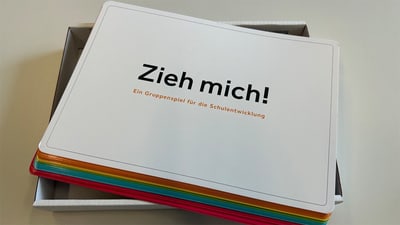 Schachtel mit einem Gruppenspiel 'Zieh mich!' für Schulentwicklung.