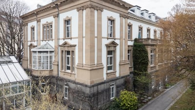 Historisches Gebäude mit klassischer Architektur und angebautem Gewächshaus.