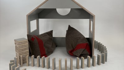 Modell eines Hauses mit Kissen und Dominosteinen.