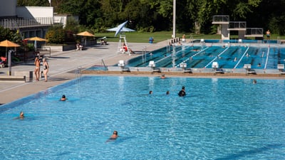 Freibad mit Schwimmern und Liegestühlen.