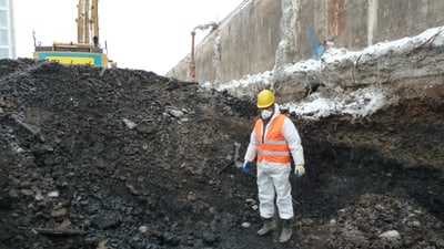 Arbeiter in Schutzkleidung an einer Baustelle mit Aushub.