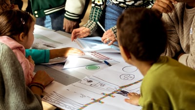Kinder und Erwachsene einer Basler Nachbarschaft verhandeln gemeinsam anhand eines Plans den Strassenraum vor ihren Häusern aus.