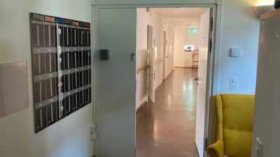 Flur mit gelbem Stuhl und Briefkästen an der Wand.
