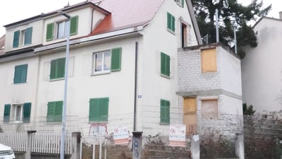 Mehrfamilienhaus mit grünen Fensterläden an der Strassenecke.