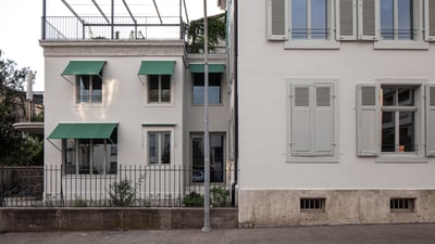Zwei Gebäude mit grünen Markisen und geschlossenen Fensterläden.