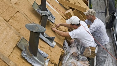 Zwei Männer arbeiten an einem Hausdach.