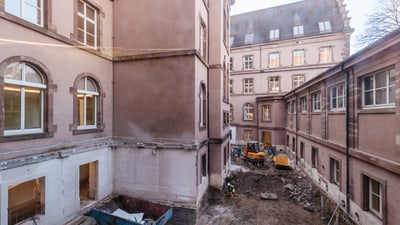 Baustelle zwischen alten Gebäuden mit Bagger.