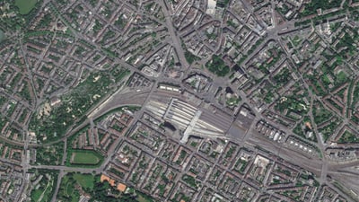 Satellitenansicht eines grossen Stadtbahnhofs mit umliegenden Gebäuden.