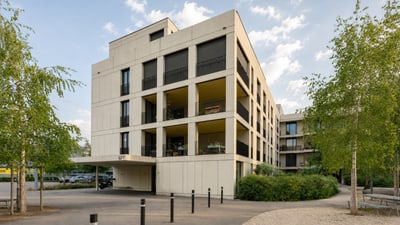Modernes Wohngebäude mit Bäumen und Gehweg.