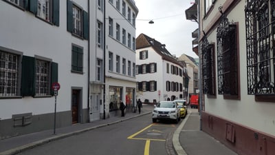 Strasse mit geparkten Autos und historischen Gebäuden in der Altstadt.",