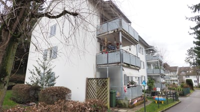 Mehrfamilienhaus mit Balkonen und kleinem Garten.