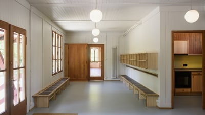 Heller Raum mit Holzbänken und Lampen.
