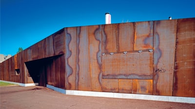 Verrostetes Gebäude mit breiten Metallplatten und blauem Himmel.