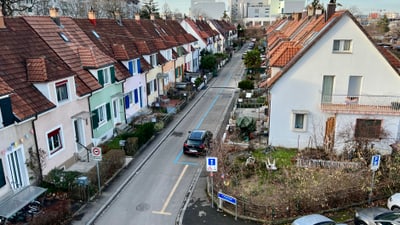 Strasse mit Reihenhäusern und Autos in einer städtischen Gegend.