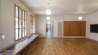 Leerer Raum mit Holzboden und Fenstern.