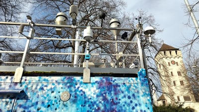 Wetterstation mit blauem Muster, im Hintergrund ein Turm.