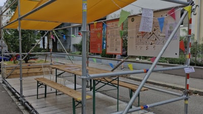 Pavillon mit Holzbänken und bunten Fahnen in der Stadt.