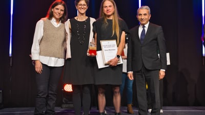 Vier Personen bei einer Preisverleihung auf der Bühne, eine hält eine Urkunde.