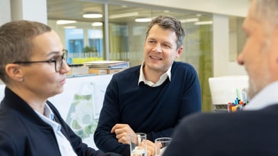 Drei Personen im Gespräch im Büro.