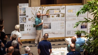 Präsentation von Architekturplänen vor Publikum in Innenraum.