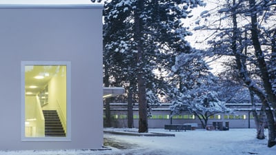 Modernes Gebäude mit beleuchteter Treppe im Winter.