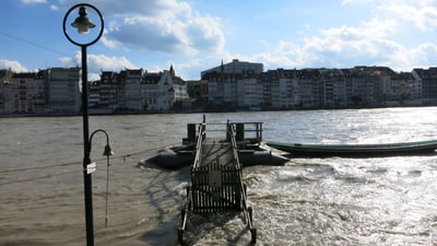 Überschwemmtes Ufer der Stadt mit Strassenlaterne und Teil einer Brücke.