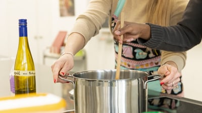 Leute kochen zusammen, rühren in einem Topf.