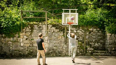 Zwei Personen spielen Basketball im Freien.