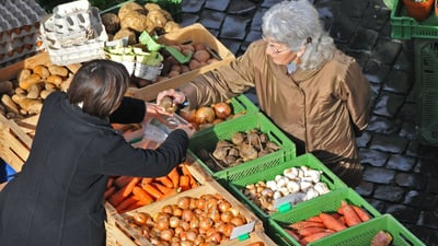 Kundin kauft Gemüse auf einem Marktstand.