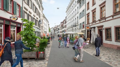 Menschen spazieren auf einer belebten Strasse in einer Stadt mit alten Gebäuden.