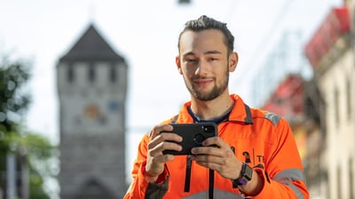 Bild von Jungem Mann in oranger Veste mit einem Messgerät in der Hand