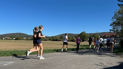 Menschen joggen auf einem Landweg bei klarem Himmel.