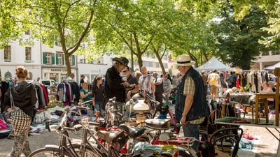 People browsing at an outdoor flea market with bicycles and various stalls.