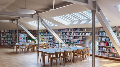 Moderne Bibliothek mit Bücherregalen, Tischen und Stühlen unter Dachfenstern.