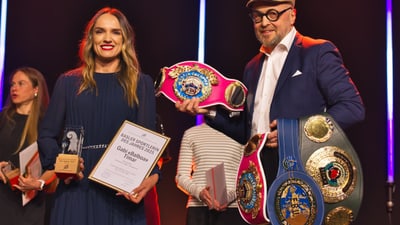 Frau und Mann mit Sportpreisen und Gürteln auf Bühne.