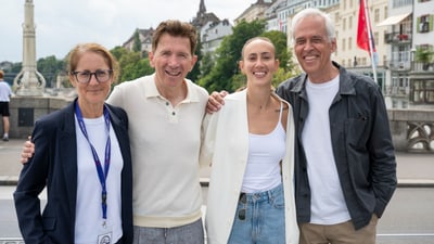 Vier Personen posieren vor einer Stadtlandschaft mit Fluss.