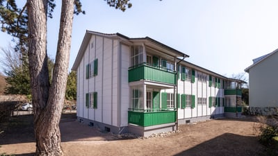 Zweistöckiges Gebäude mit grünen Fensterläden und Balkonen.