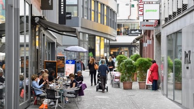 Menschen, die in einer städtischen Gasse in einem Strassencafé sitzen.