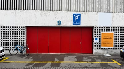 Rote Garagentür mit Fahrrad und Parkzeichen Horburg.