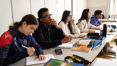 Gruppe von Schülern im Klassenzimmer beim Lernen am Tisch sitzend.
