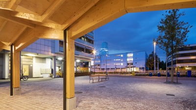 Moderne Holzüberdachung in einer städtischen Platzumgebung bei Dämmerung.