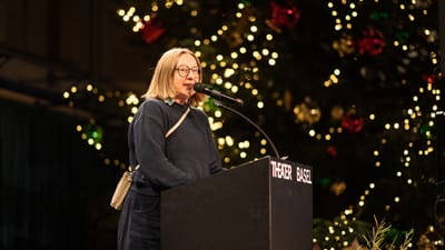 Frau am Rednerpult mit Weihnachtsbaum im Hintergrund bei Theater Basel.