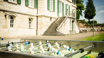 Tischfussballspiel vor einem Gebäude mit grünen Fensterläden.