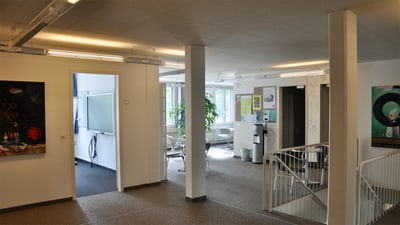Aufenthaltsraum mit Kunst an den Wänden und Treppe.